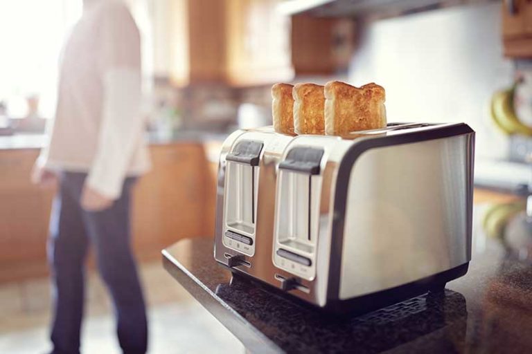 toaster with toasted bread in and woman in background